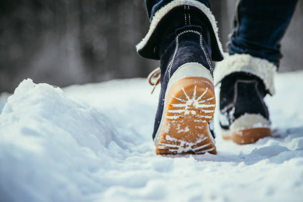 Close-up view of someone wearing winter boots and walking in the snow