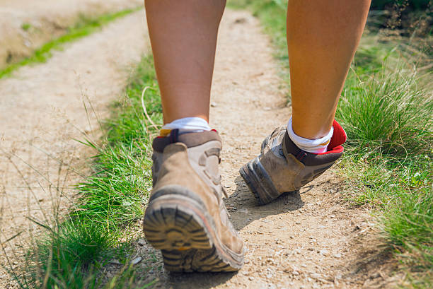 A person hiking in boots on a dirt path rolling their right ankle as they walk.